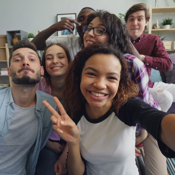 Diverse group of people smiling in a bright room, ready for a yoga class.